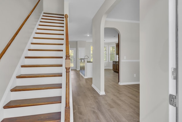 staircase featuring crown molding and wood-type flooring