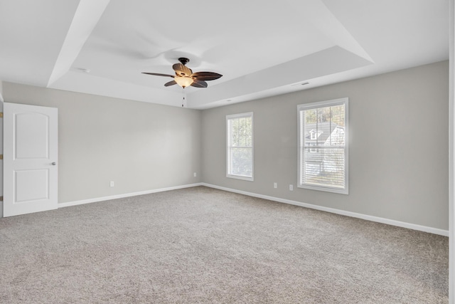 carpeted spare room featuring a raised ceiling and ceiling fan