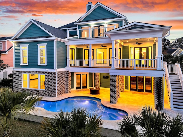 back house at dusk featuring ceiling fan and a balcony