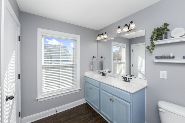 bathroom featuring wood finished floors, toilet, baseboards, and a sink