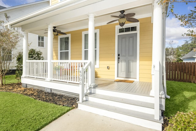entrance to property with fence, ceiling fan, covered porch, and a yard