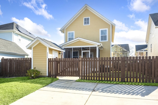 traditional-style home featuring a gate, a fenced front yard, a front yard, a sunroom, and ceiling fan