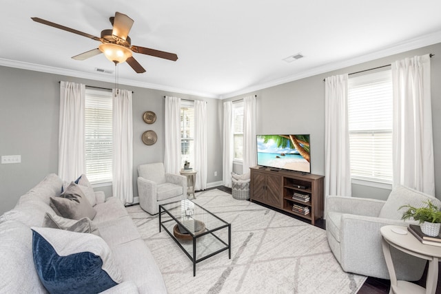living area with plenty of natural light, visible vents, crown molding, and ceiling fan