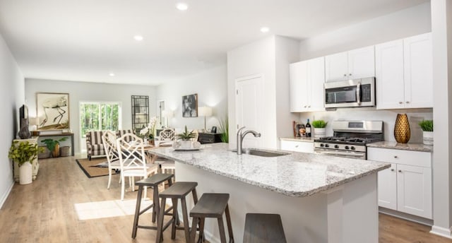 kitchen featuring an island with sink, sink, white cabinets, and stainless steel appliances