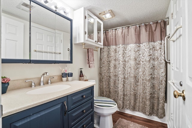 bathroom with vanity, toilet, a textured ceiling, and wood finished floors