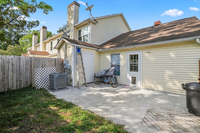 rear view of property with fence, central AC unit, a chimney, and a patio area