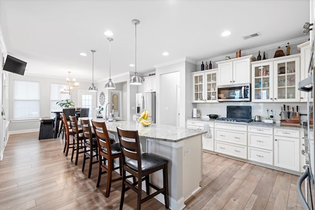 451 Spectrum Rd, Summerville, SC 29486 - kitchen featuring appliances with stainless steel finishes, ornamental molding, a large island with sink, tasteful backsplash, and light wood-style flooring