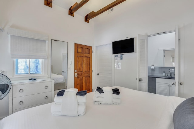 bedroom featuring beamed ceiling and ensuite bathroom