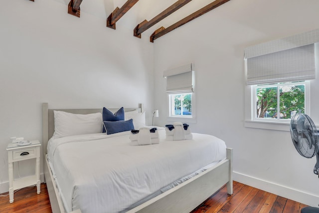 bedroom featuring multiple windows, dark hardwood / wood-style flooring, and beamed ceiling