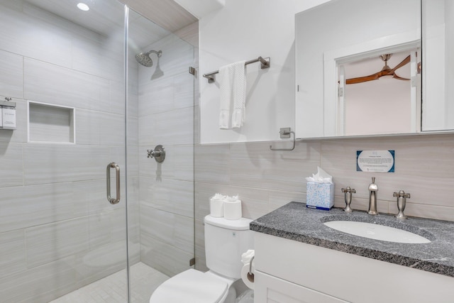 bathroom with walk in shower, tile walls, vanity, and toilet