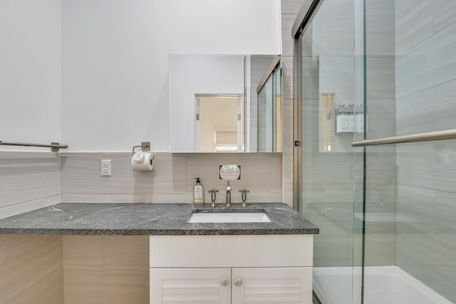 bathroom featuring tile walls, vanity, decorative backsplash, and a shower with shower door