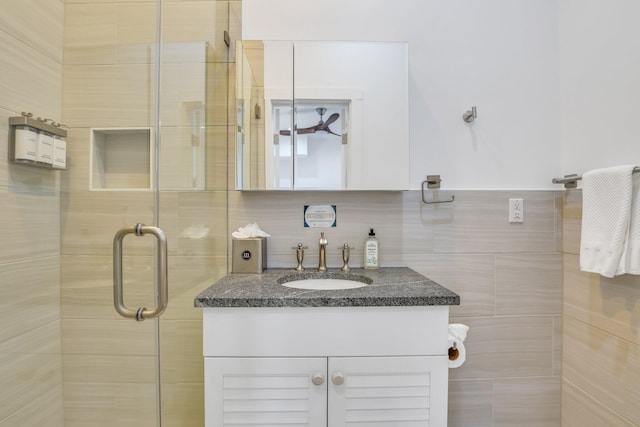 bathroom with vanity, a shower with shower door, and tile walls