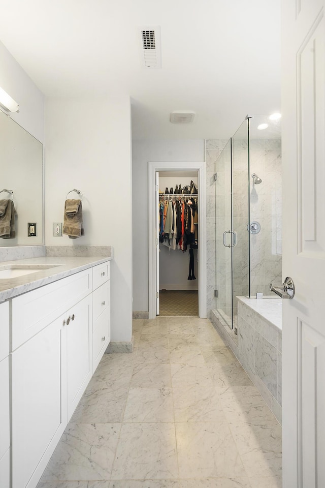 bathroom featuring a stall shower, visible vents, marble finish floor, a garden tub, and a spacious closet