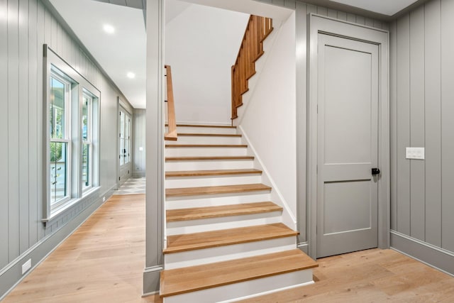 staircase featuring wooden walls and hardwood / wood-style flooring