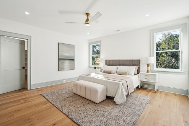 bedroom featuring multiple windows, ceiling fan, and light hardwood / wood-style flooring