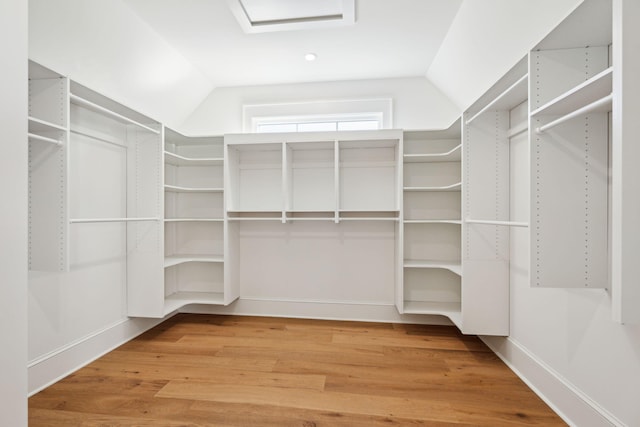 walk in closet with hardwood / wood-style flooring and vaulted ceiling