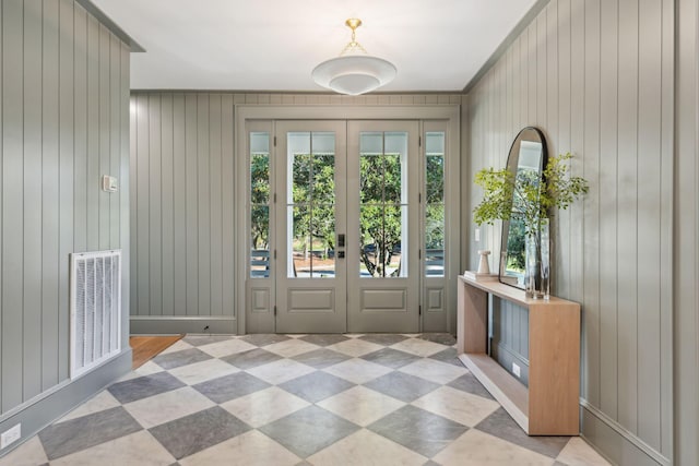 doorway with wooden walls, french doors, and crown molding