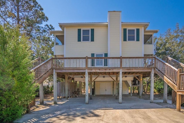 rear view of house featuring stairs, a chimney, a carport, and concrete driveway