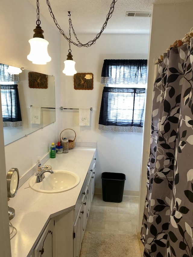 bathroom with a textured ceiling, vanity, and tile patterned floors