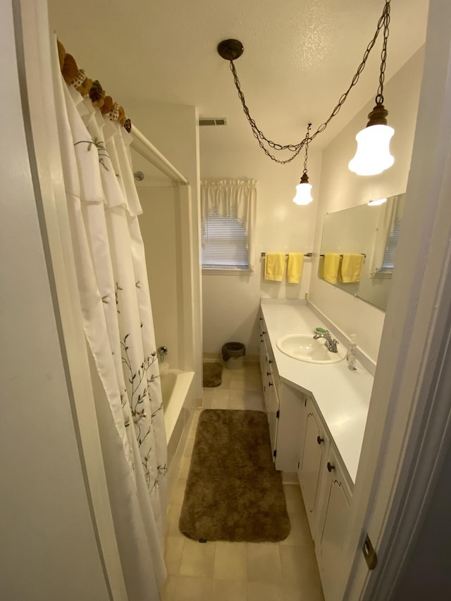 bathroom with tile patterned floors, shower / bathtub combination with curtain, vanity, and a textured ceiling