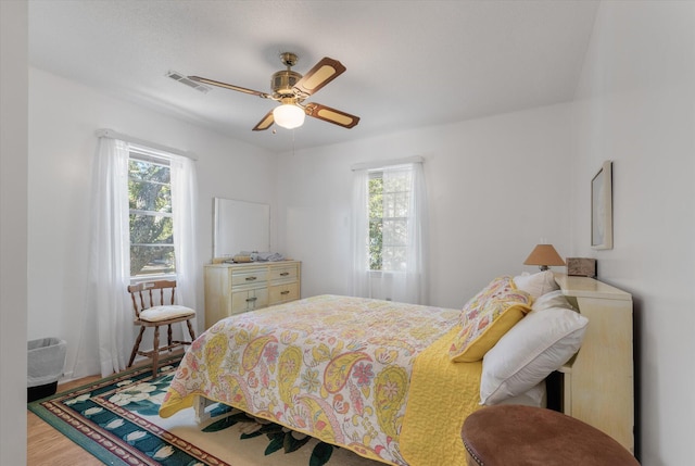 bedroom with hardwood / wood-style floors, multiple windows, and ceiling fan