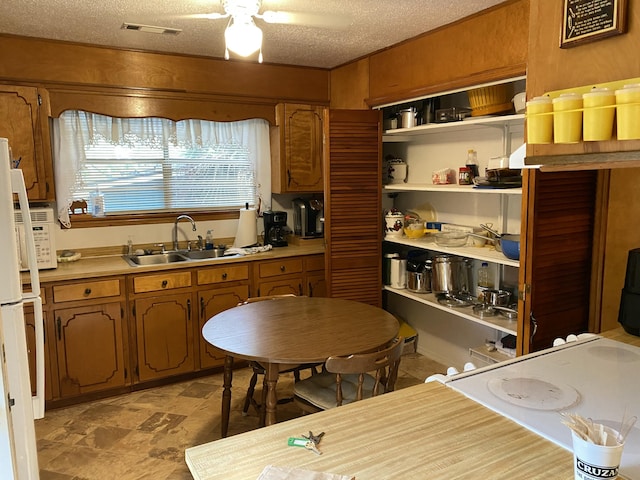 kitchen with a textured ceiling, ceiling fan, and sink