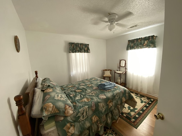 bedroom with wood-type flooring, a textured ceiling, and ceiling fan