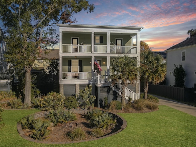 coastal home featuring a lawn, a balcony, and a porch