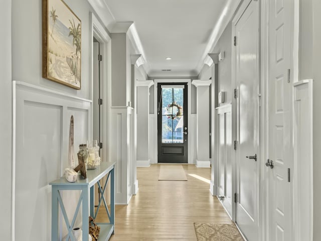 doorway featuring light wood-type flooring and crown molding