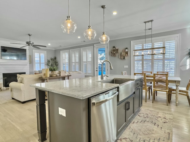 kitchen with decorative light fixtures, a large fireplace, a center island with sink, and stainless steel dishwasher