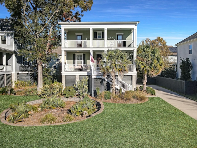 coastal home with a porch, a balcony, and a front lawn