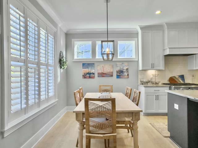 dining area featuring a notable chandelier, light wood-type flooring, and crown molding