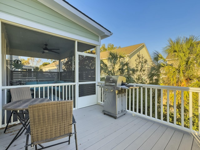 wooden deck featuring area for grilling, ceiling fan, and a sunroom