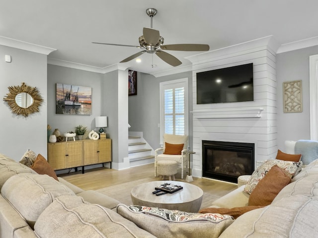 living room with ceiling fan, a fireplace, light hardwood / wood-style floors, and ornamental molding