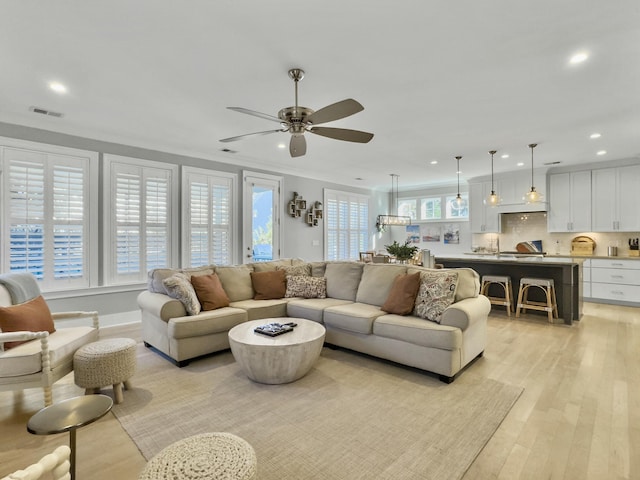 living room with light hardwood / wood-style floors, ceiling fan, and crown molding