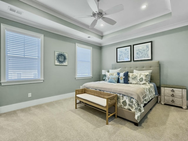 carpeted bedroom with a raised ceiling, ceiling fan, and crown molding