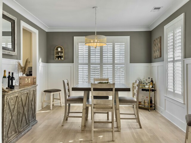 dining room featuring light hardwood / wood-style flooring, a notable chandelier, and ornamental molding