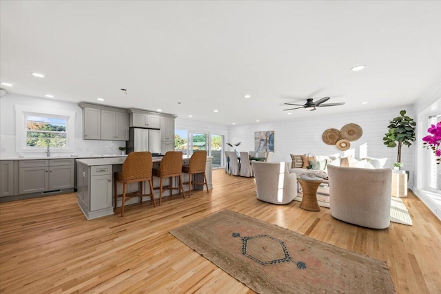 living room featuring light hardwood / wood-style floors, sink, plenty of natural light, and ceiling fan