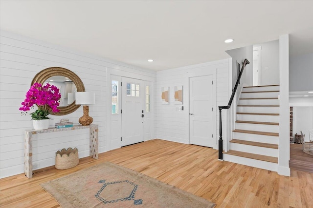 foyer entrance with wooden walls and hardwood / wood-style floors