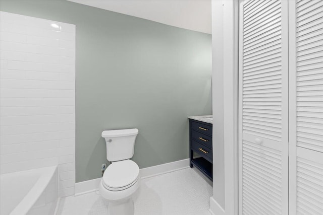 bathroom featuring toilet, vanity, tile patterned floors, and a bath