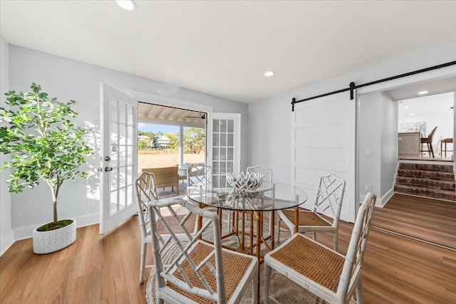 dining area featuring french doors, a barn door, and hardwood / wood-style flooring