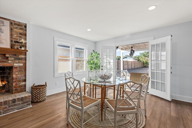 dining room featuring a healthy amount of sunlight, dark hardwood / wood-style flooring, and a fireplace