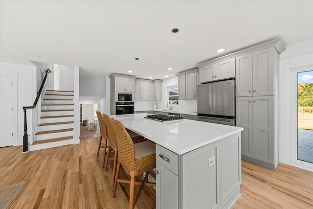 kitchen featuring black appliances, a kitchen breakfast bar, gray cabinetry, and a kitchen island