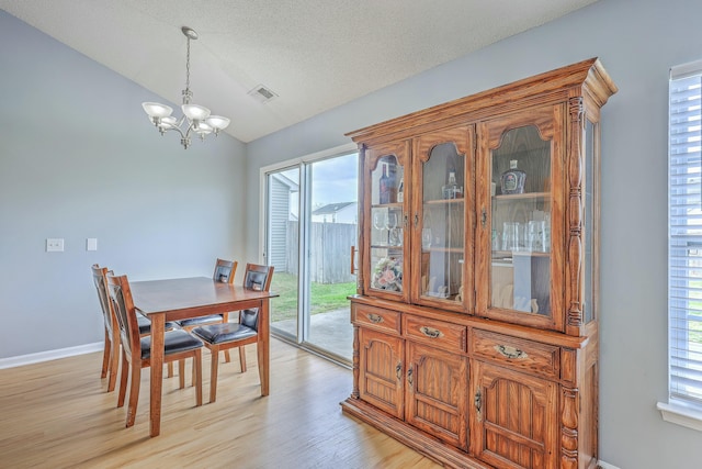 dining room featuring visible vents, vaulted ceiling, a textured ceiling, a notable chandelier, and light wood-type flooring