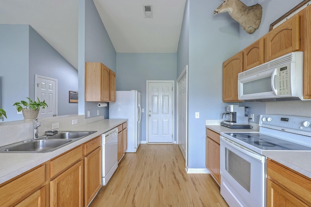 kitchen featuring white appliances, light countertops, and a sink