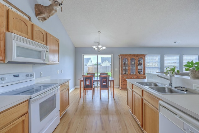 kitchen featuring a chandelier, white appliances, light countertops, and a sink