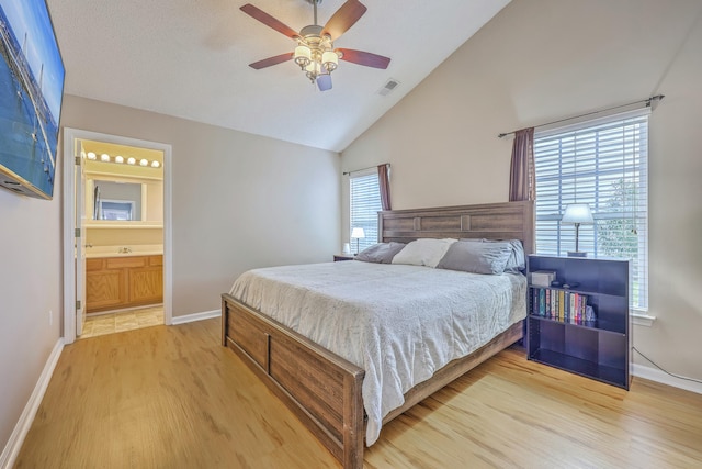 bedroom featuring visible vents, connected bathroom, baseboards, vaulted ceiling, and light wood-style flooring