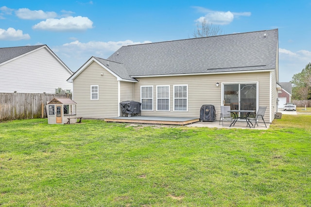 back of property with a patio area, a lawn, roof with shingles, and fence