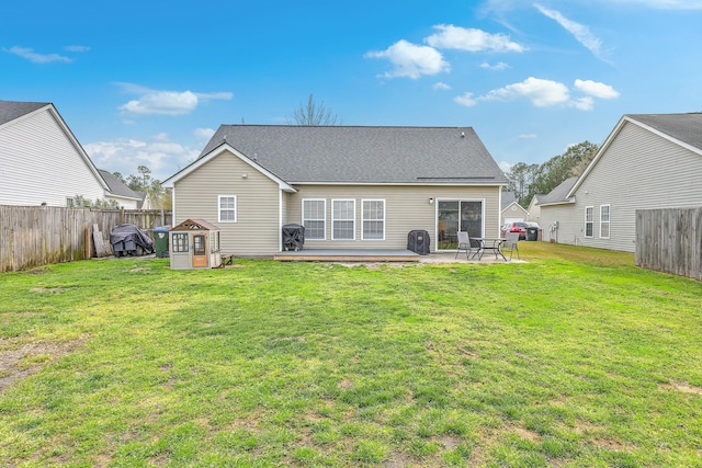 back of property with a yard, a patio, a fenced backyard, and roof with shingles