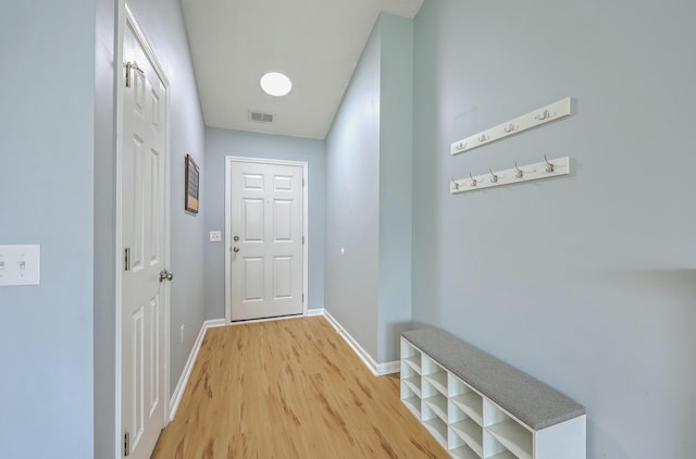 hallway featuring visible vents, light wood-type flooring, and baseboards